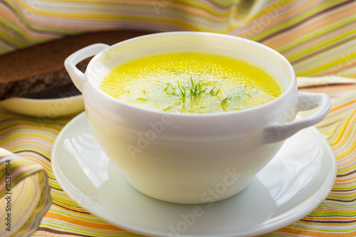 Clear soup with dill in a white bowl