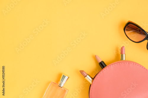 Top view of cosmetic bags with lipsticks, glasses, perfume