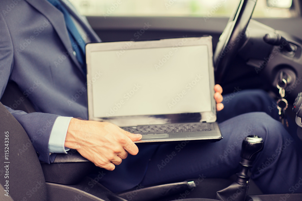 close up of young man with laptop driving car close up of young man with laptop driving car