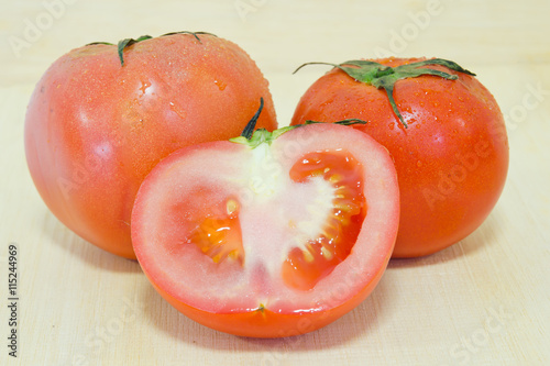 Tomato fruit with half cross section isolated on wooden backgrou photo