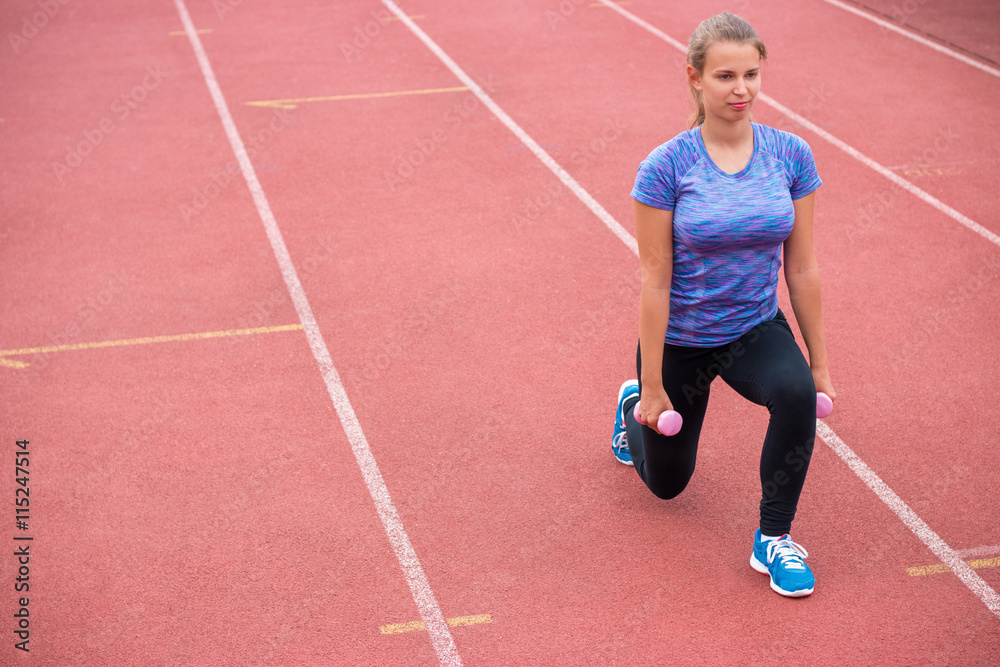 Young athletic woman exercising with dumbbells outdoors