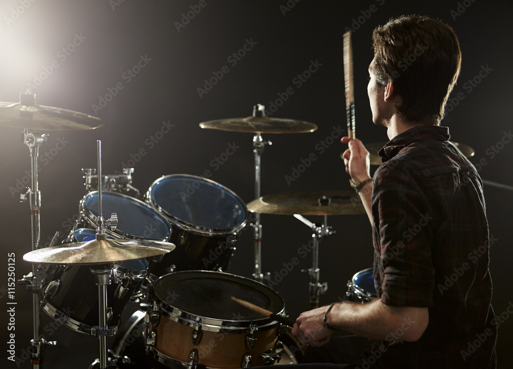 Rear View Of Drummer Playing Drum Kit In Studio Rear View Of Drummer Playing Drum Kit In Studio