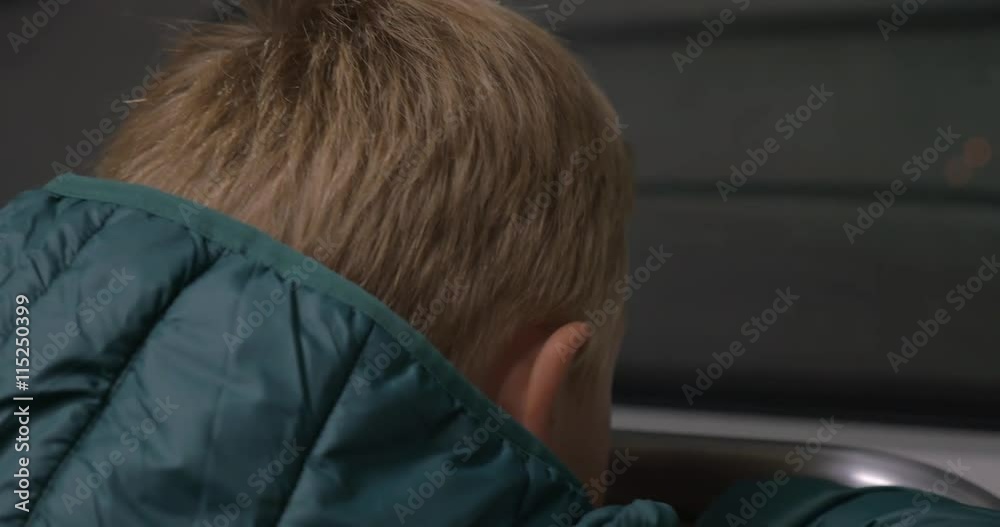 Close-up back shot of a child looking through the window of moving underground train Close-up back shot of a child looking through the window of moving underground train