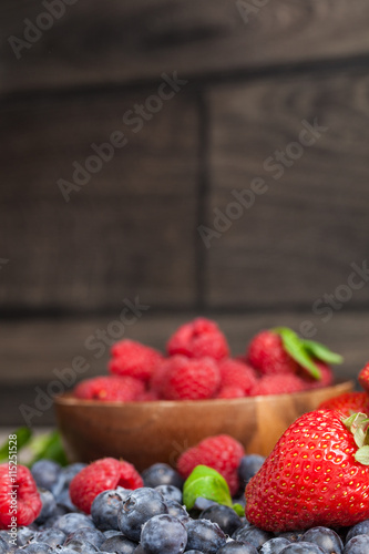 fresh raspberries, blueberries and strawberries on wooden background