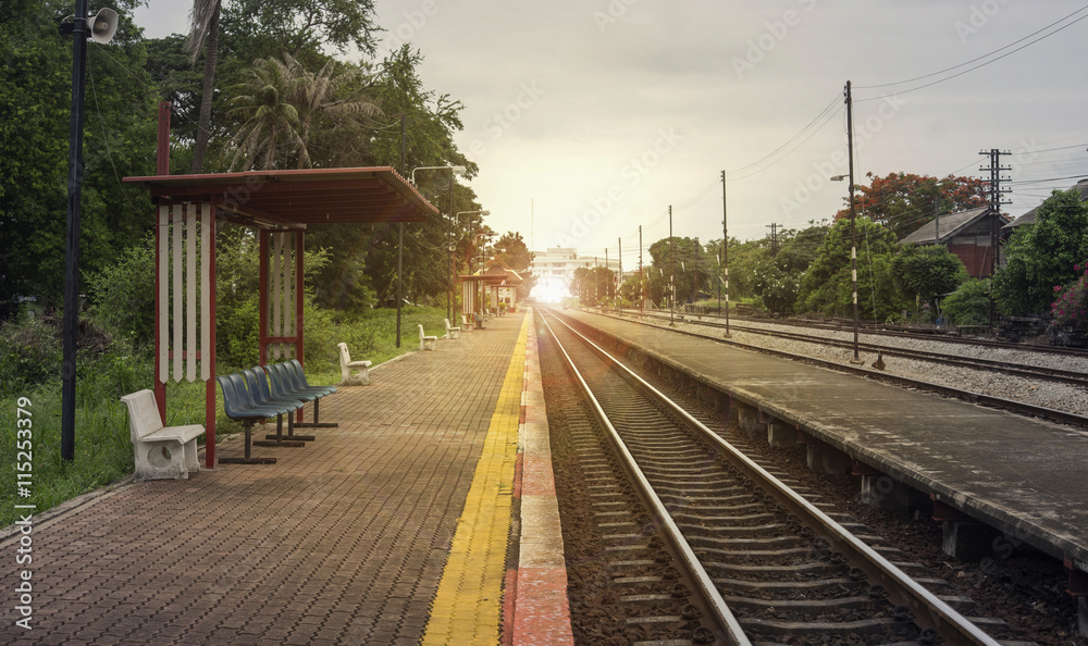 view of the length of railway with pavement at left side of railway,filtered image, light effect and flare added,selective focus,mean 