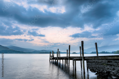 Moody dusk clouds over Derwentwater Lake with wooden jetty. © _Danoz