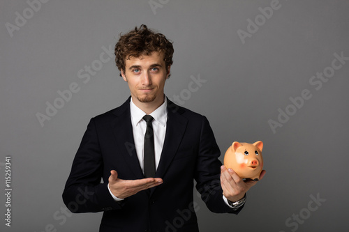 elegant man with piggybank on gray background photo
