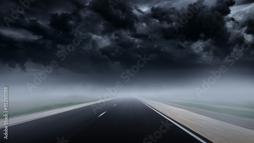 Drive at empty asphalt road to thunderstorm through mist