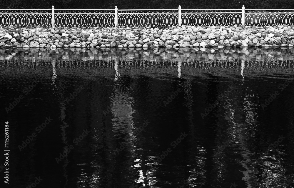 Obraz premium Horizontal black and white fence reflections on lake surface bac
