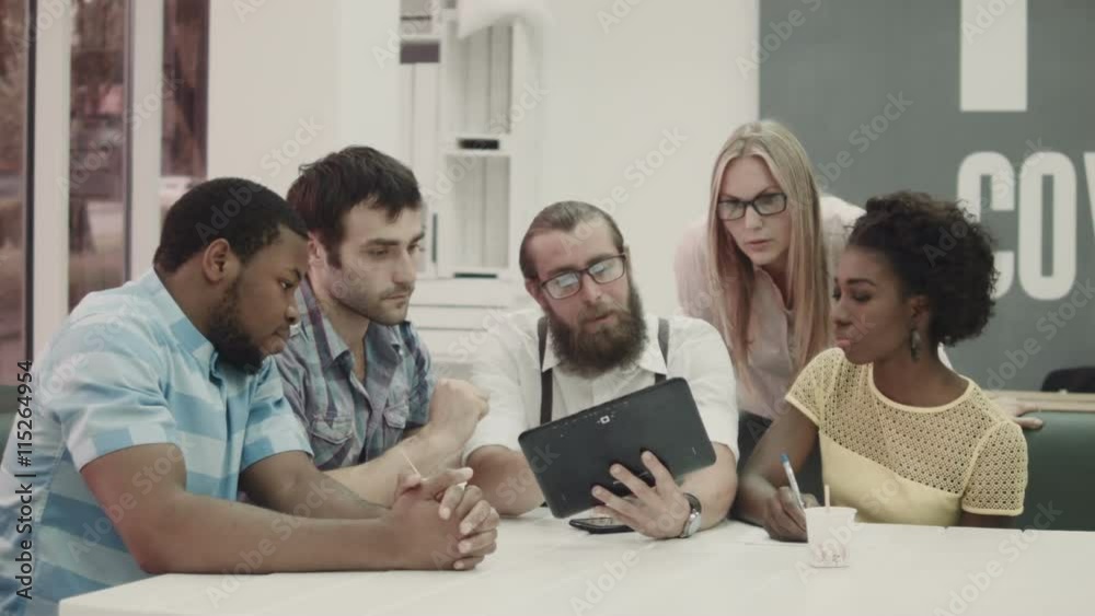 Adults in co-working office using tablet and talking. Adults in co-working office using tablet and talking.