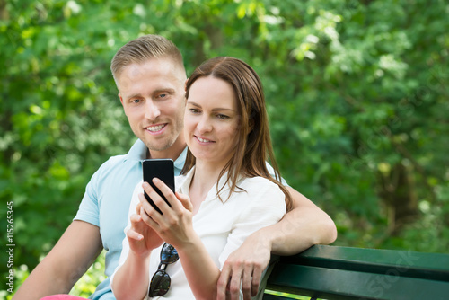 Couple Using Mobile Phone In Garden