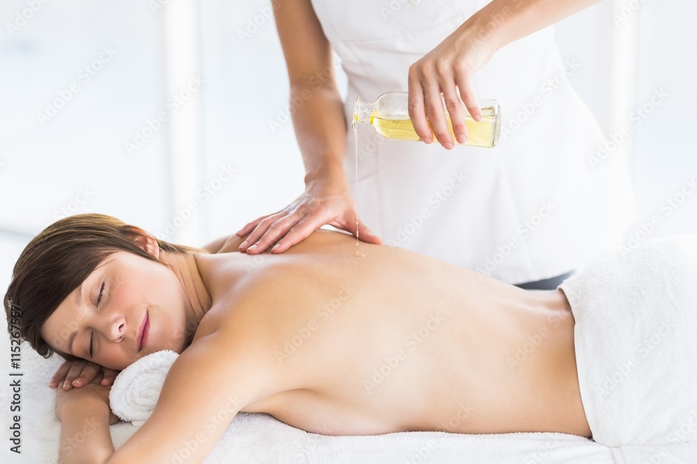 Fototapeta premium Midsection of masseur pouring oil on woman back