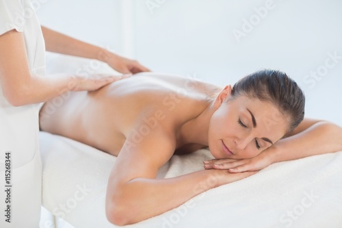 Relaxed naked woman receiving back massage