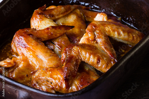 Baked chicken wings with barbecue sauce in clay bowl