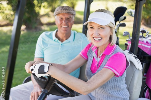 Smiling mature couple sitting in golf buggy
