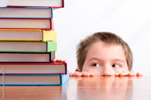 Thoughtful young schoolboy eyeing up his books