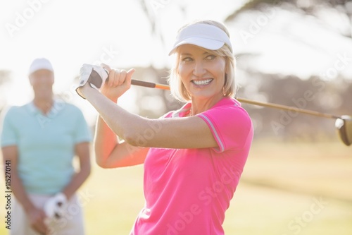 Confident mature woman carrying golf club by man 