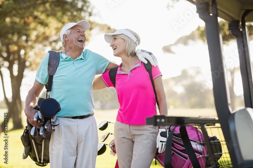 Cheerful mature golfer couple with arm around