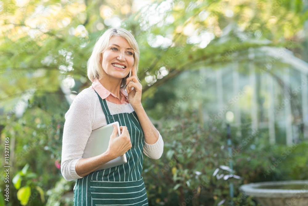 Female gardener smiling while talking on cellphone Female gardener smiling while talking on cellphone