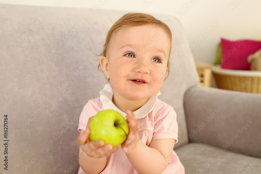 Baby with apple on sofa in room Baby with apple on sofa in room