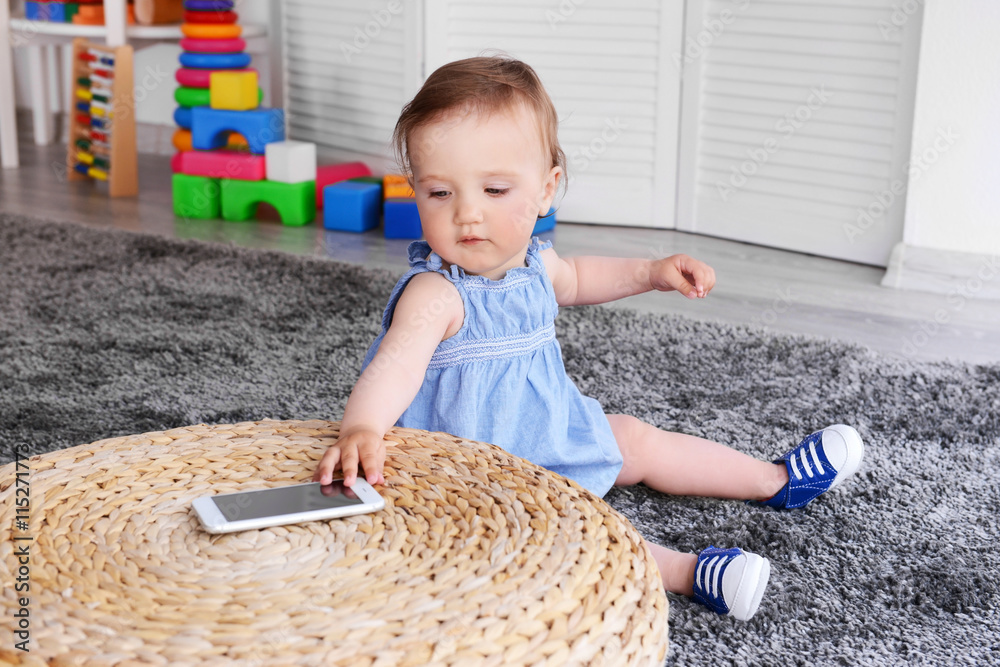 Naklejka premium Little girl with telephone on carpet