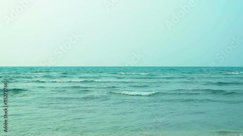Light gray color of an overast sky highlights the calm, warm water of a tropical beach, with tiny, gentle waves. 4k video