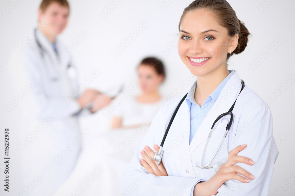 Cheerful smiling female doctor on the background with doctor and his patient in the bed. High level and quality of medical service concept. Cheerful smiling female doctor on the background with doctor and his patient in the bed. High level and quality of medical service concept.