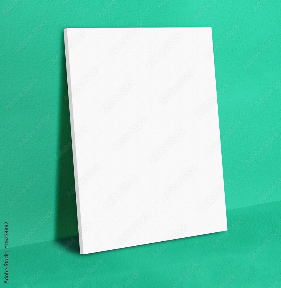 Blank white poster canvas frame leaning at green concrete paint