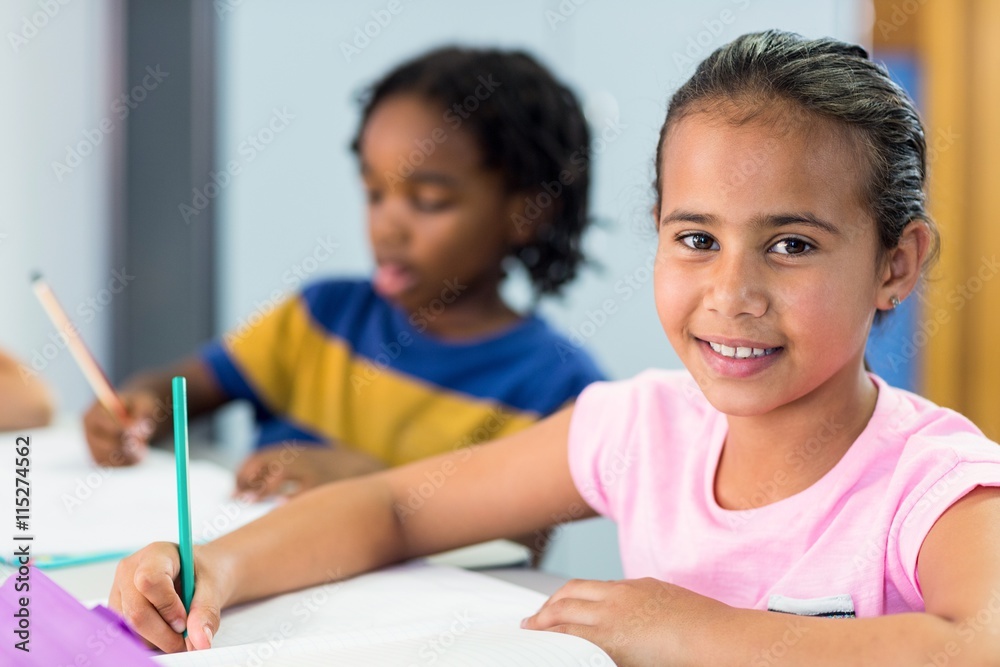 Smiling schoolgirl with classmate writing on book Smiling schoolgirl with classmate writing on book