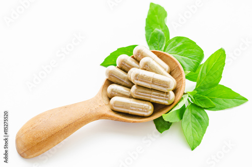 Herbal medicine capsules in wooden spoon.