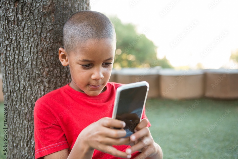 Elementary boy using mobile phone at park Elementary boy using mobile phone at park