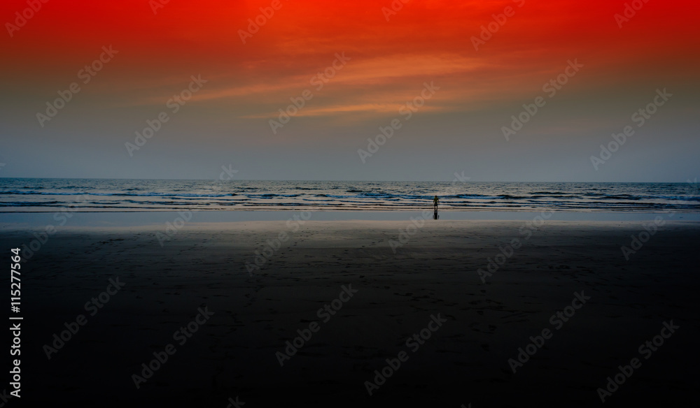 Horizontal wide child watching red sunset on beach ocean backgro