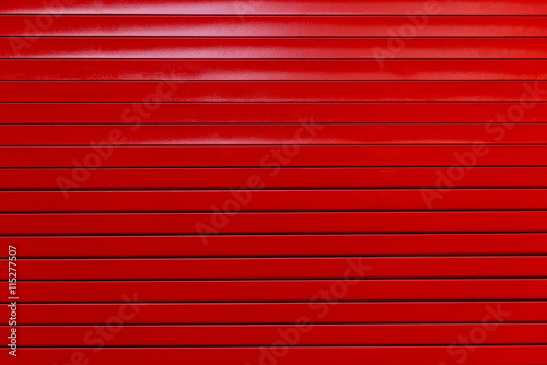 Red painted metal garage door or wall. Red garage door with black stripes. Black and red metal wall background.