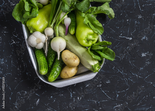 Fresh green and white vegetables - cucumbers, peppers, radish, radish, garlic, onion, potato, zucchini on a dark background. Healthy vegetarian food