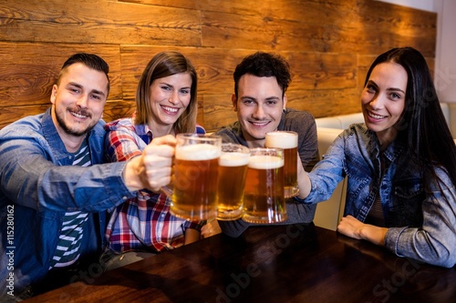 Portrait friends toasting beer at restaurant