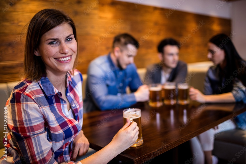 Woman holding beer mug with friends in background