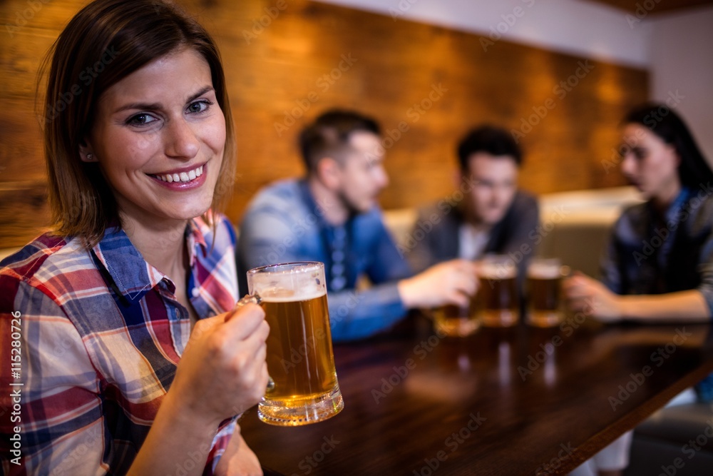 Woman holding beer mug while friends in background