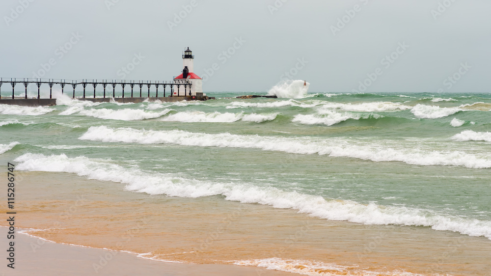 Lake Michigan waves crash against the East Pierhead Outer Lighthouse and catwalk, in Michigan City, Indiana.