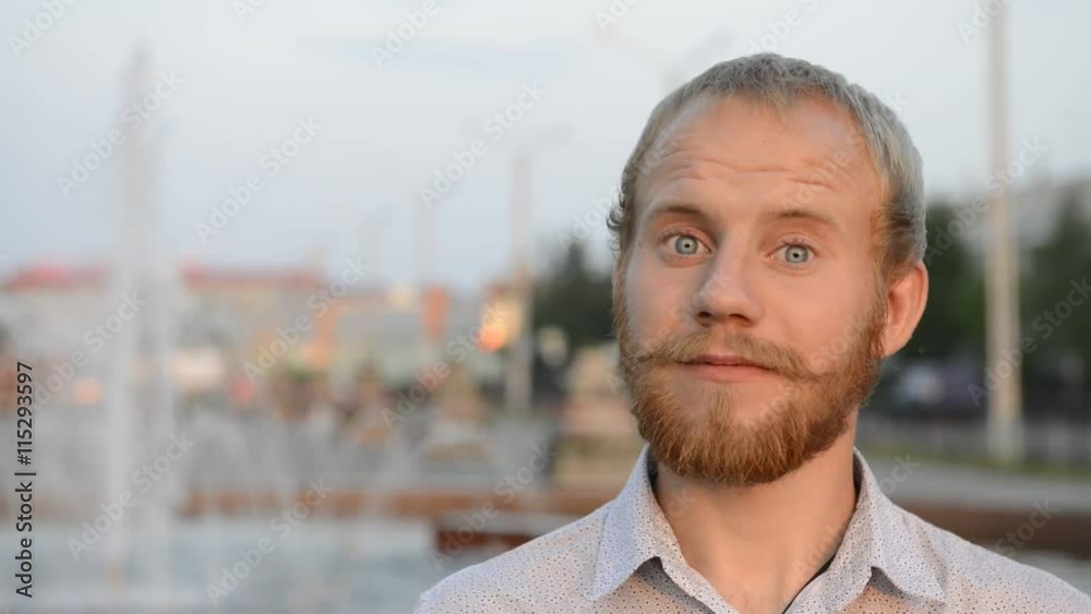 blond man with blue eyes and beard near the fountain looking at the camera
