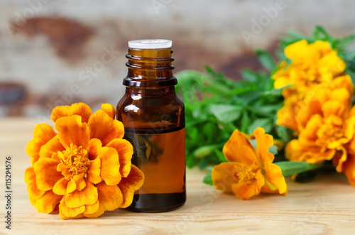 Small bottle of essential marigold oil (Tagetes flowers extract, tincture, infusion) photo