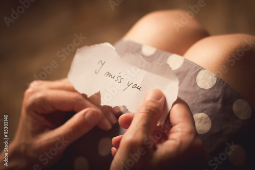 Woman holding a paper note with the text I miss you photo