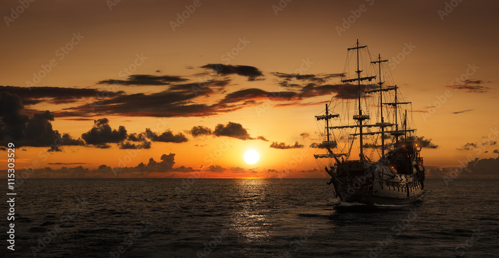 Pirate ship at the open sea at the sunset with copy space