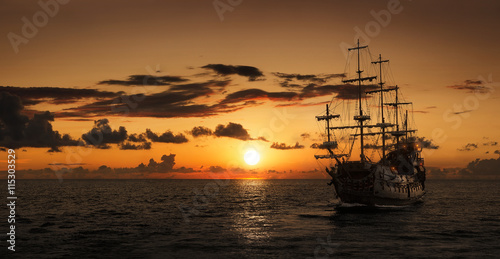 Pirate ship at the open sea at the sunset with copy space