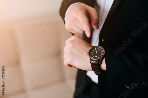 businessman in black suit look at his expensive swiss wristwatch on his hand and watching the time