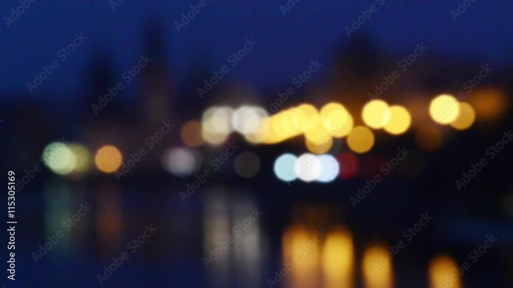 View to the Old Town in the center of Prague from Vltava river with water reflection at nght with illumination and traffic, travel blurred outdoor european background