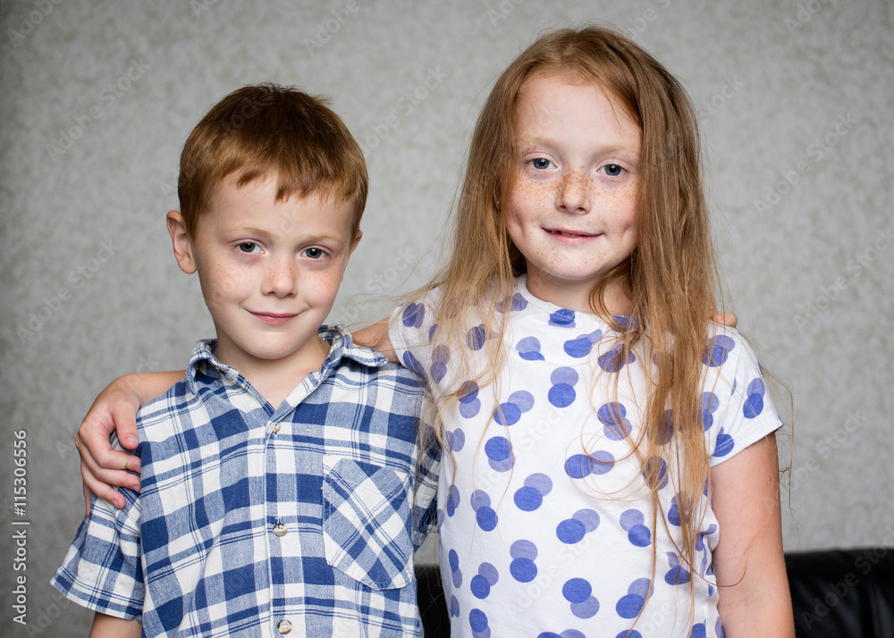 Little redheaded children - brother and sister are hugging each other indoors Little redheaded children - brother and sister are hugging each other indoors