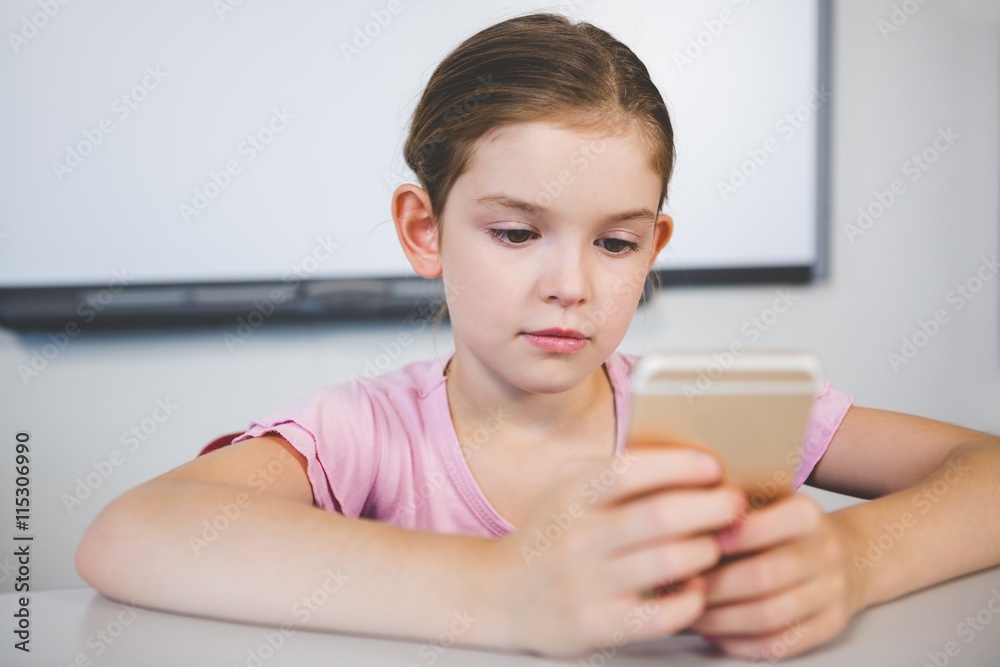 Schoolgirl using mobile phone in classroom Schoolgirl using mobile phone in classroom
