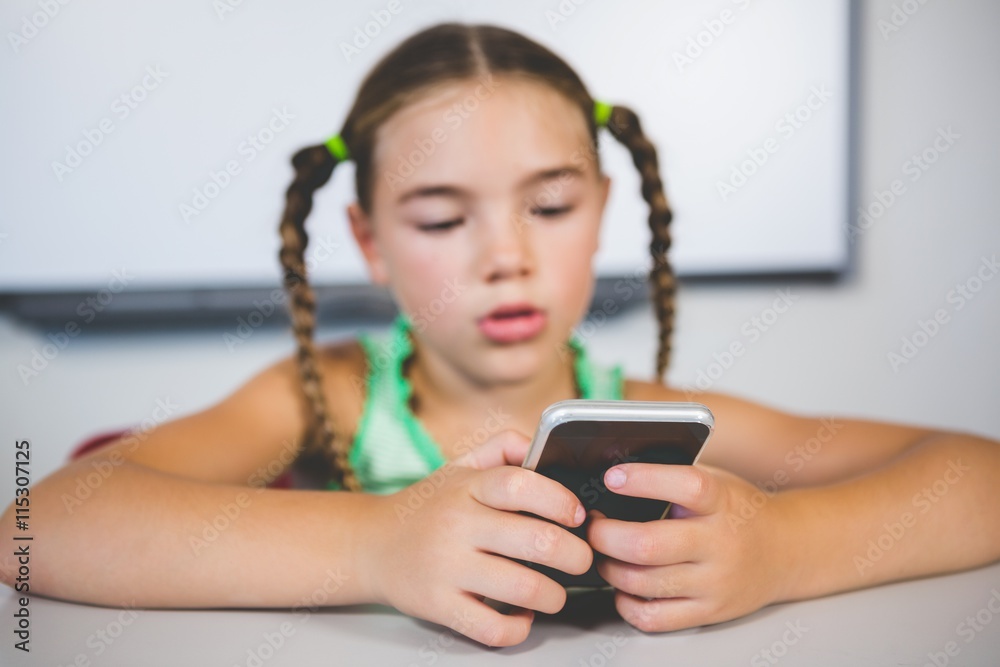 Schoolgirl using mobile phone in classroom Schoolgirl using mobile phone in classroom