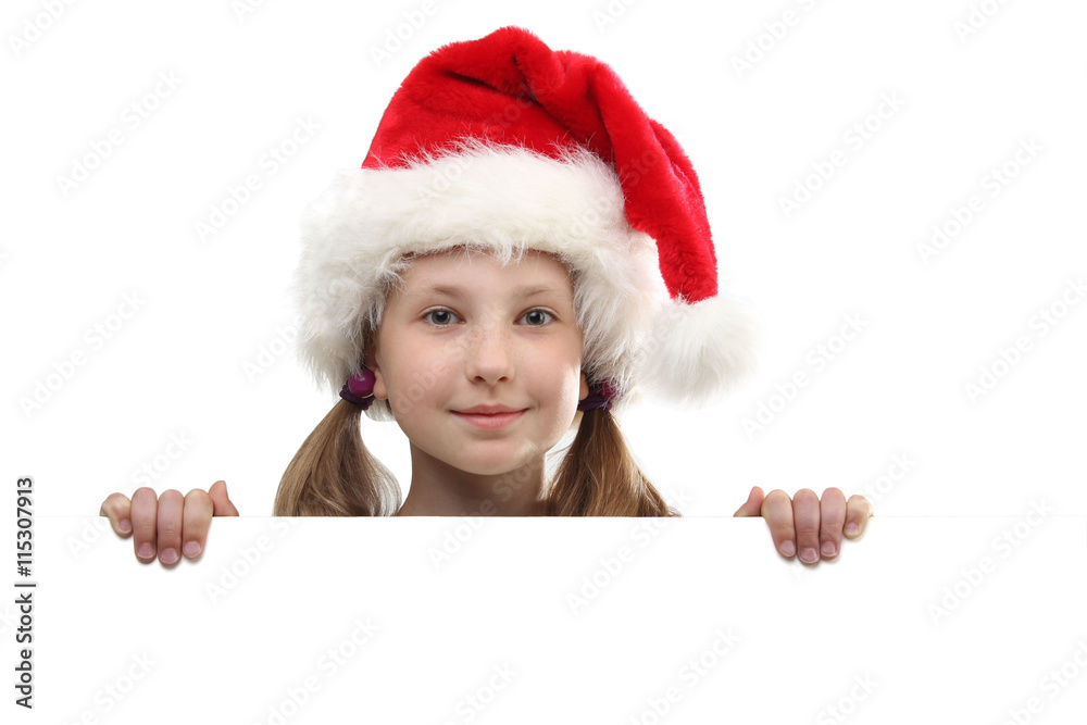 the portrait of smiling little girl on Santa Claus hat peeking by the white board looking at camera isolated on white background. the portrait of smiling little girl on Santa Claus hat peeking by the white board looking at camera isolated on white background.