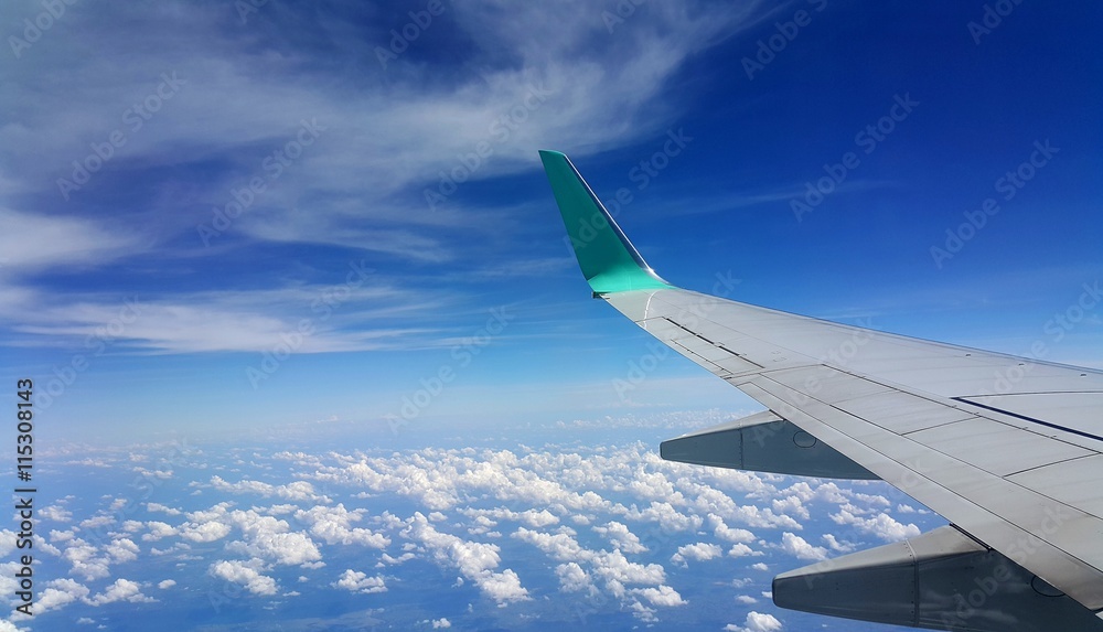 Fototapeta premium Wing of an airplane flying above the clouds. people looks at the sky from the window of the plane.
